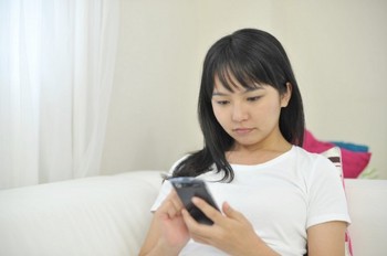 携帯で出会い系のサイトの男性にメールを打っている女性